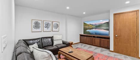 A living room with a leather sofa, a coffee table, a flat-screen TV, and a wooden cabinet.