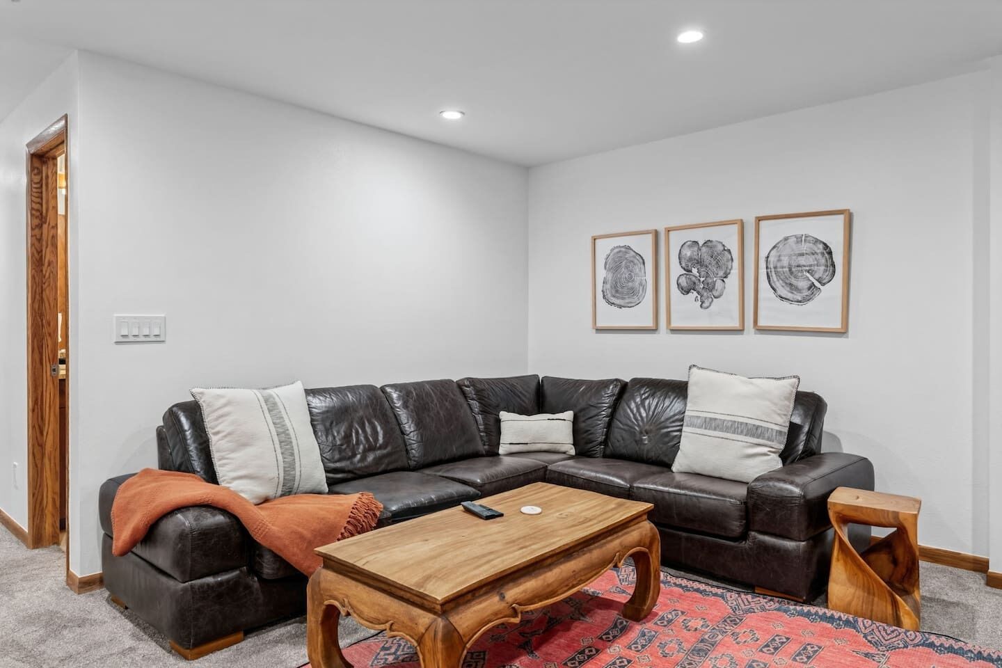 Ein stilvolles Wohnzimmer mit einem ledernen Ecksofa, einem Holztisch und einem gemusterten Teppich.