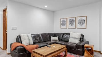 Ein stilvolles Wohnzimmer mit einem ledernen Ecksofa, einem Holztisch und einem gemusterten Teppich.