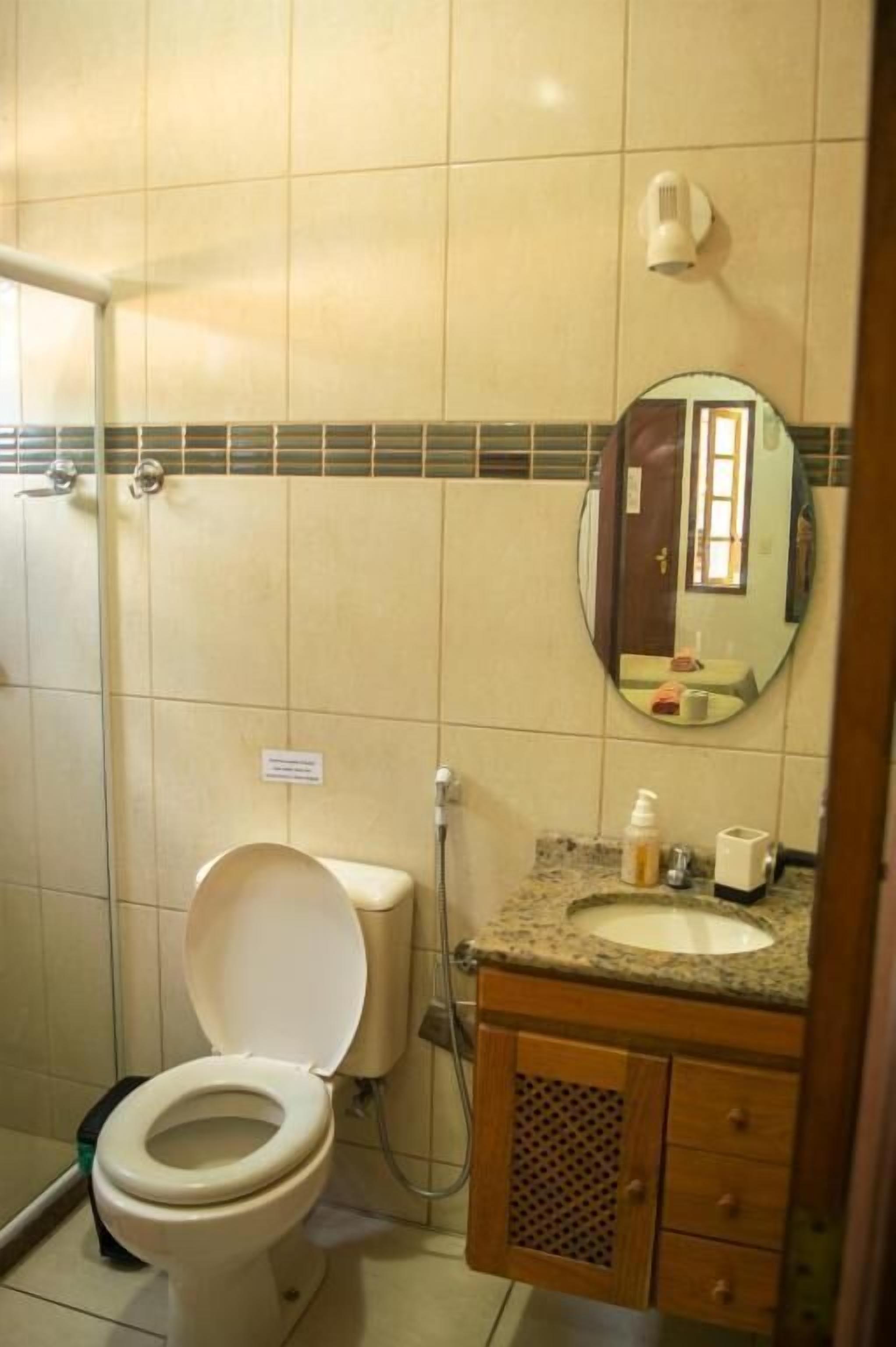 A bathroom with a toilet, sink, mirror, and shower.
