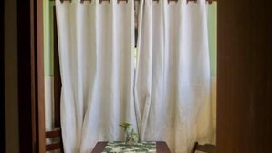 A room with a wooden table, two chairs, a curtain, and a door. - MOANA  (Buzios)