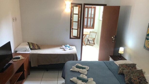 A hotel room with two beds, a TV, a desk, and a chair. - MOANA  (Buzios)