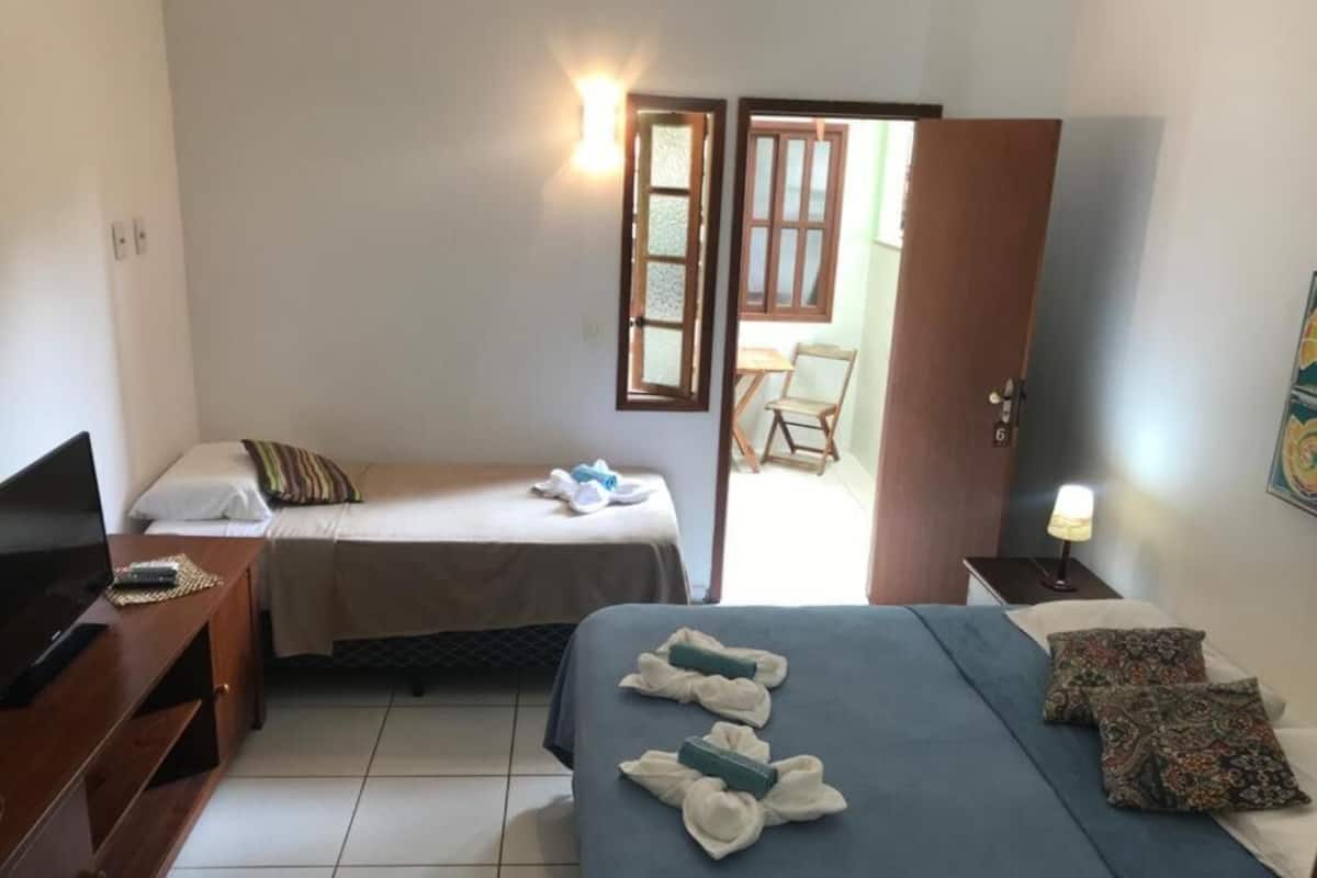 Ein Hotelzimmer mit zwei Betten, einem Fernseher, einem Schreibtisch und einem Sessel.