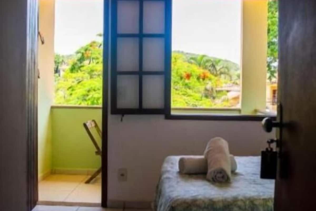 Ein Zimmer mit Bett, Fenster und Blick ins Grüne.
