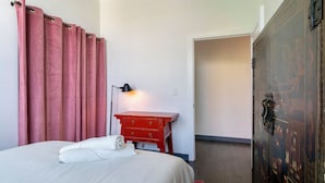 A hotel room with a bed, a red dresser, a lamp, and a wardrobe. - Holiday Lofts NYC (Newark)