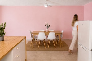 A modern kitchen with a dining area, featuring a wooden table, white chairs, and a ceiling fan. - Pink Paradise | 2 Min to Beach | Sleeps 5 (Surfers Paradise)