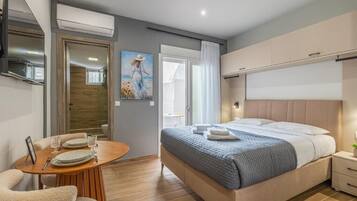 Ein modernes Hotelzimmer mit Bett, Nachttisch und einem Essbereich mit Tisch und Stühlen.