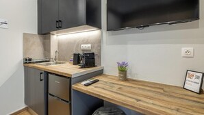 Eine kompakte Küche mit eingebautem Geschirrspüler, einer Kaffeemaschine und einem kleinen Spülbecken.