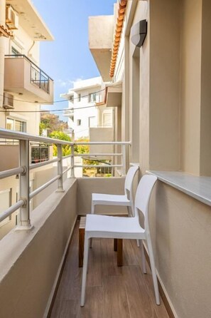 A narrow balcony with white chairs, a metal railing, and a view of adjacent buildings. - Raise Heraklion 4 Moments (Heraklion)