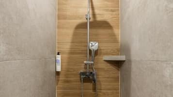 A shower with a handheld showerhead, a wall-mounted faucet, and a handheld showerhead.