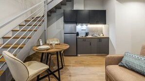 Eine kompakte Küche mit modernen Geräten, ein Essbereich mit Tisch und Stühlen sowie eine Treppe zu einer weiteren Ebene.