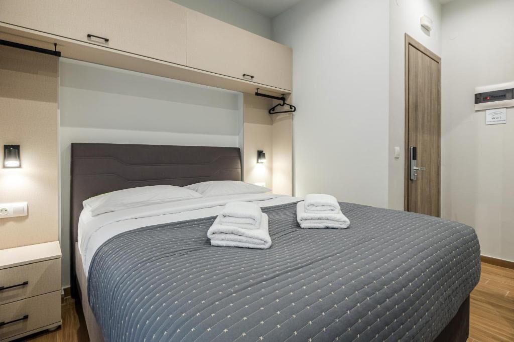 A hotel room with a bed, bedside tables, a wardrobe, and a door.
