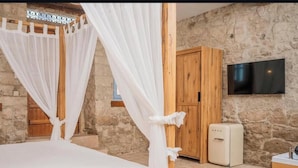 A bedroom with a stone wall, a wooden wardrobe, a TV mounted on the wall, and a bed with white bedding. - Terrific 9-bedroom hotel with AC in vibrant İzmir
Location point in the alacati (İzmir)