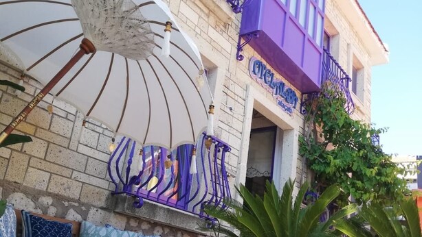 A building with a stone facade, a wooden bench, a table, and a purple umbrella. - Terrific 9-bedroom hotel with AC in vibrant İzmir
Location point in the alacati (İzmir)