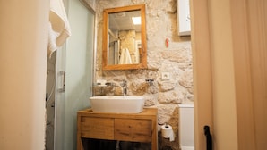 A bathroom with a stone wall, a wooden vanity, a white sink, a mirror, and a towel hanging on the wall. - Terrific 9-bedroom hotel with AC in vibrant İzmir
Location point in the alacati (İzmir)