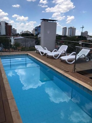 A swimming pool with lounge chairs and a view of the city skyline. - Shopping del Sol Zone (Asunción)