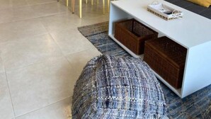 Een moderne woonkamer met een eethoek en een keuken op de achtergrond, plus een groot raam.