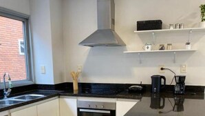 Een moderne keuken met een groot eiland, een ingebouwde oven en een roestvrijstalen afzuigkap.
