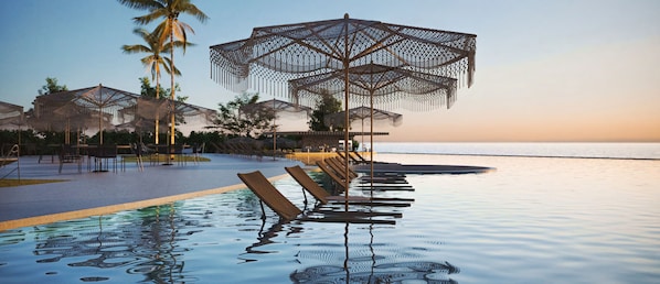 Un espace aménagé au bord de la piscine, avec des chaises longues et des parasols, des palmiers et une vue sur la mer.