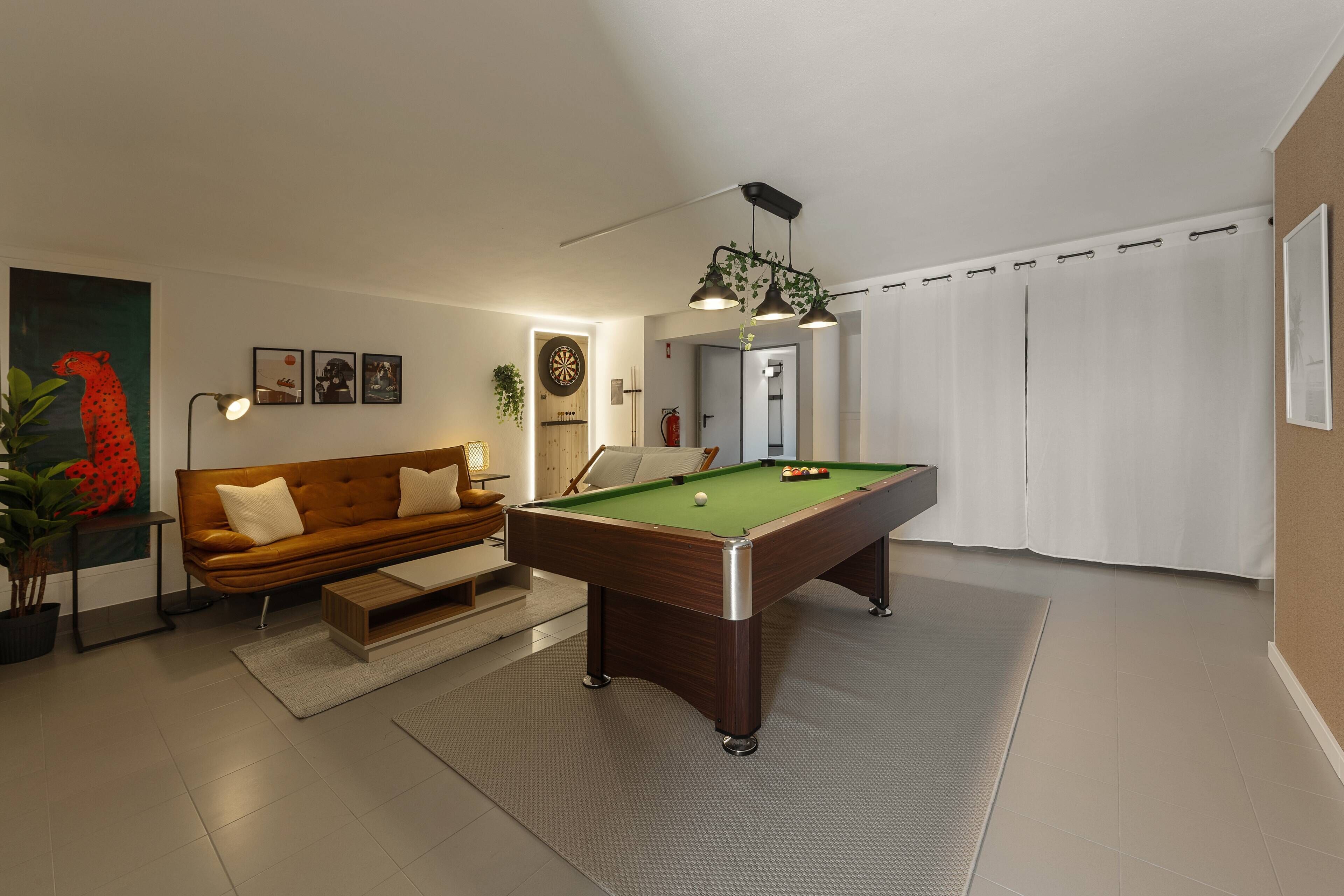 A modern living room with a pool table, a sofa, and a ceiling fan.