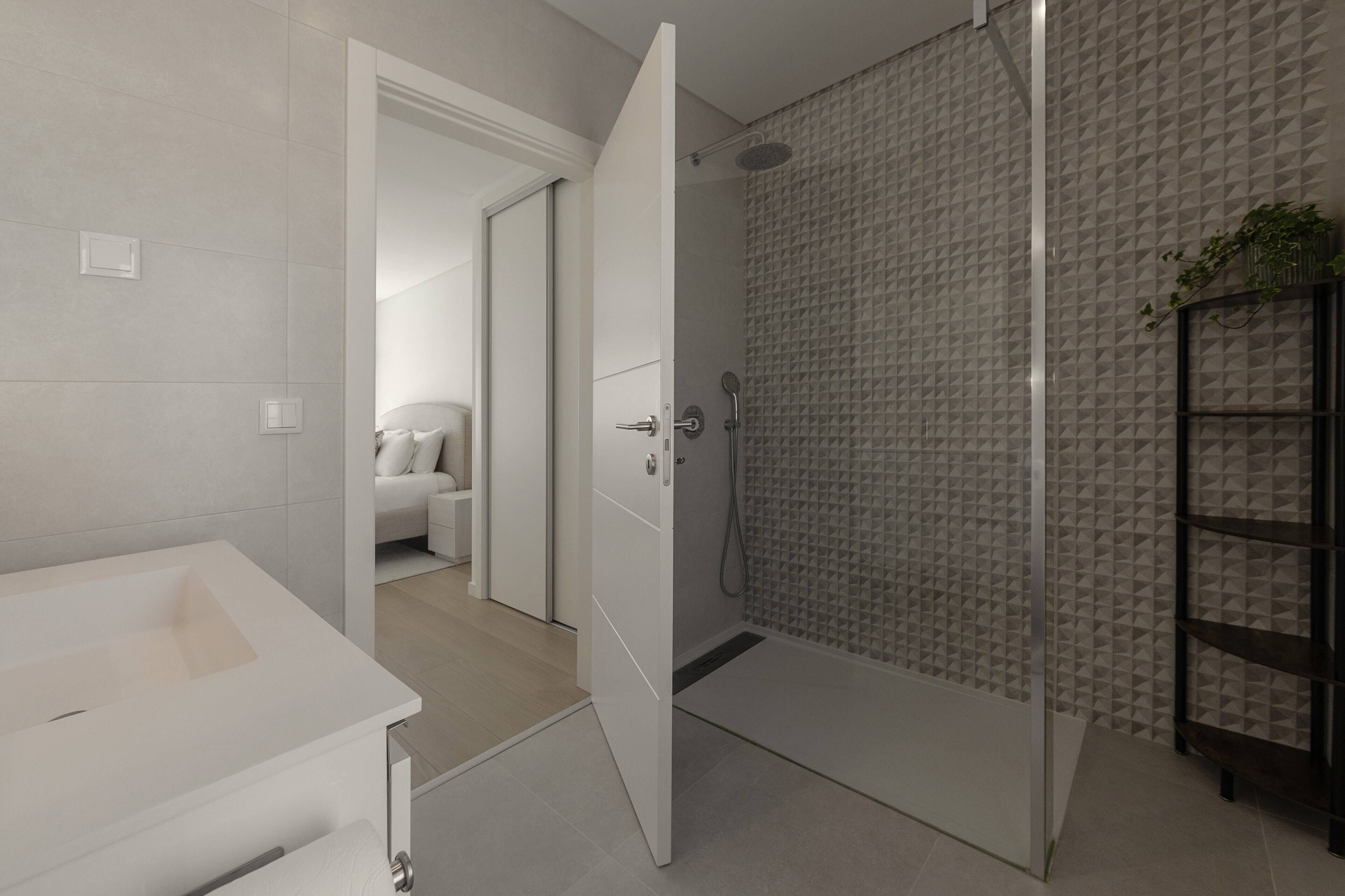 Een moderne badkamer met een douche, toilet en wastafel.