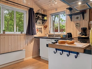 Eine moderne Küche mit Holzwänden, einem großen Fenster und einem eingebauten Backofen.