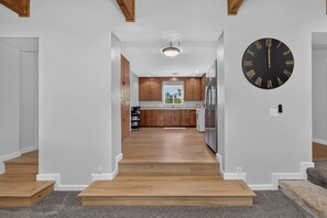 A modern kitchen with wooden cabinets, a black clock, and a view to the dining area. - The Overlook at Hidden Cove - newly listed property on the lake with dock (Fairland)