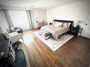 A bedroom with a bed, bedside tables, a chair, a dresser, and a window with curtains.