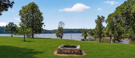 Ett grönområde med en eldstad av sten och träd.