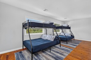 Ein Zimmer mit zwei Etagenbetten, einem Fenster mit Jalousien und einem gemusterten Teppich.