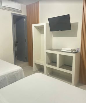 A hotel room with a bed, a TV mounted on the wall, a wardrobe, and a door leading to another room. - Marogo Boutique (Acapulco)