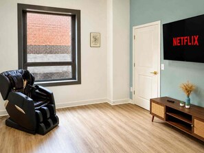A room with a massage chair, a television mounted on the wall, and a wooden cabinet. - Spacious! 4th Street Live, Brown Theatre, KFC Yum! (Louisville)