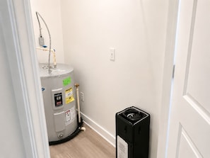 Ein Badezimmer mit Warmwasserbereiter, einer schwarzen Mülltonne und einer weißen Tür.