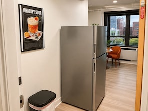 Eine moderne Küche mit einem Edelstahl-Kühlschrank, einem Mülleimer und einem Bild an der Wand.