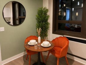 A dining area with a round table, two chairs, a mirror, and a window. - Dwtwn! Waterfront Park, Brown Theatre, 4thStreet (Louisville)