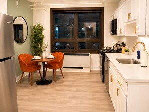 A modern kitchen with a dining area, a large window, and a view of the city at night. - Dwtwn! Waterfront Park, Brown Theatre, 4thStreet (Louisville)