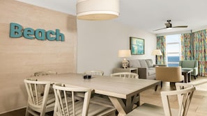 Ein modernes Hotelzimmer mit Essbereich, einer Couch, einer Lampe und Meerblick.