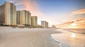 Ein Hotel direkt am Strand mit mehreren Hochhäusern, einem Sandstrand und Blick auf den Ozean.