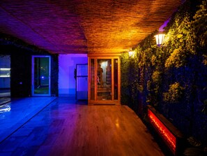 A modern interior with a wooden floor, a glass door entrance, and a wall covered in greenery.