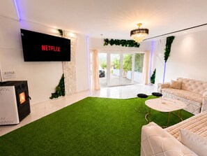Un salon moderne avec un téléviseur à écran plat, une cheminée, un canapé et une table basse.