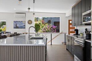 Una cucina moderna con una grande isola, elettrodomestici in acciaio inossidabile e vista su un giardino fiorito.