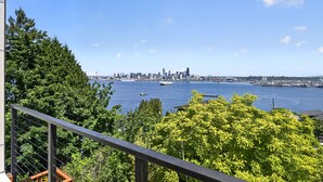 Une vue sur les gratte-ciel d’une ville, avec une étendue d’eau au premier plan et une balustrade de balcon au premier plan.