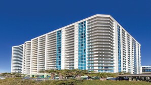 Ein hoch aufragendes Hotel mit zahlreichen Balkonen, einem modernen architektonischen Design und blauem Himmel im Hintergrund.