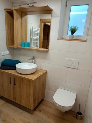 Une salle de bain avec un meuble-lavabo en bois, un lavabo blanc et des toilettes.