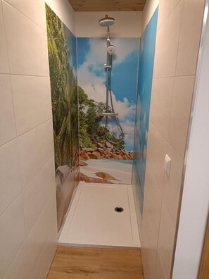 Une douche ornée d’une fresque représentant une scène de plage, avec des murs carrelés et un sol en bois.