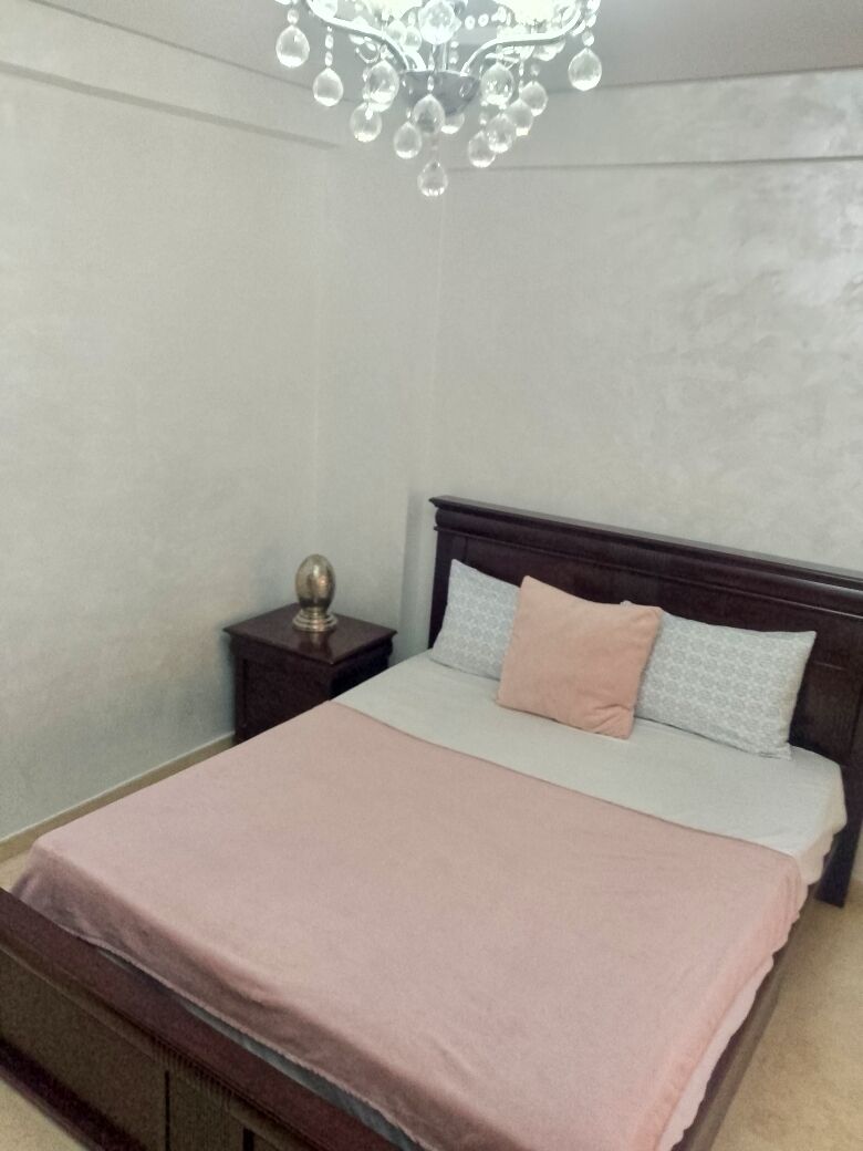 Un dormitorio con cama, mesita de noche, candelabro y cabecera de madera.