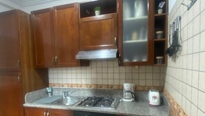 A kitchen with wooden cabinets, a gas stove, a sink, and a coffee maker. - appartement chic en plein centre (Marrakesh)