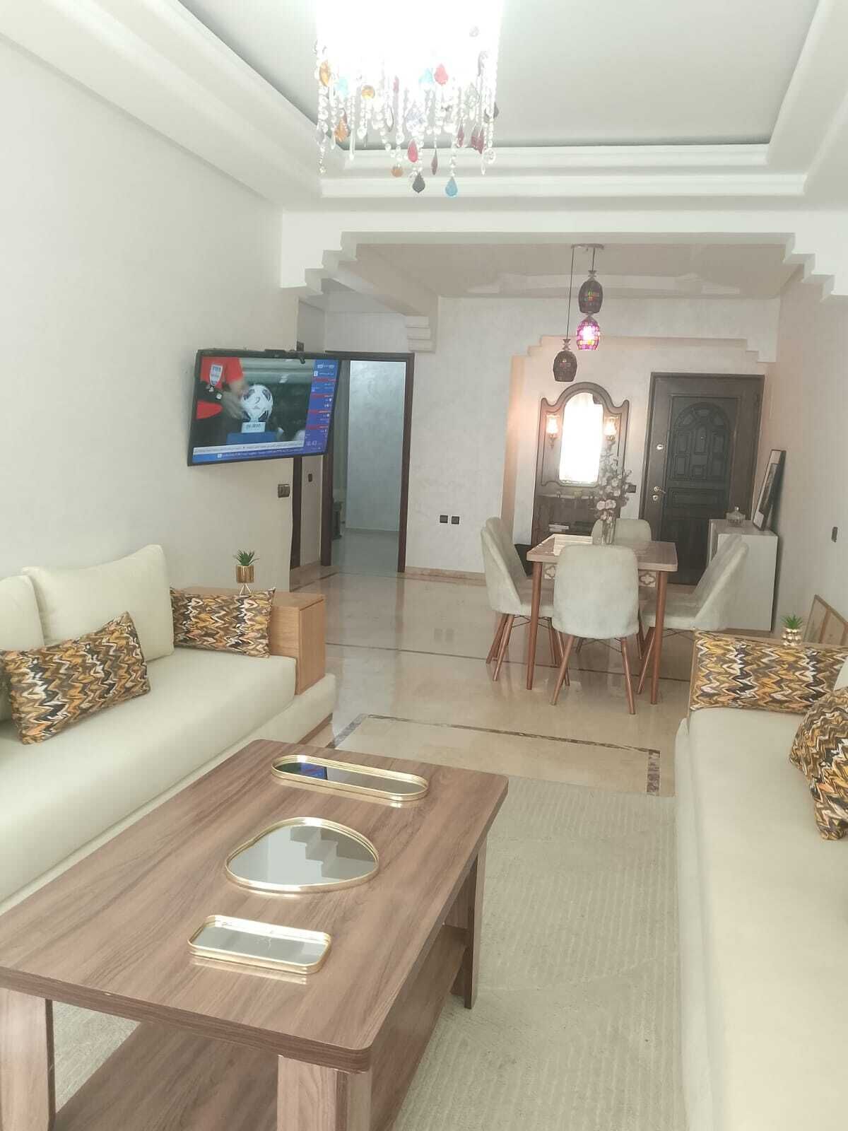Un salon comprenant un canapé, une table basse, un téléviseur et un coin repas avec des chaises et une table.