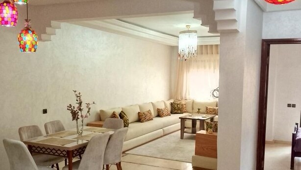 A spacious living area with a dining table, sofas, and a chandelier. - appartement chic en plein centre (Marrakesh)