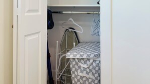 A walk-in closet with shelves, a hanging rack, and an ironing board. - Fully AC 2 Bed 2 Bath Apartment (Surrey)